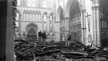 Firemen survey the fire damage to the South Transept of York Minster after the fire.
