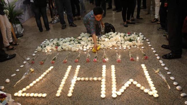 A Malaysia Airlines crew member places a flower next to candles forming the letters MH17 after  multi-faith prayers for the victims (AP)